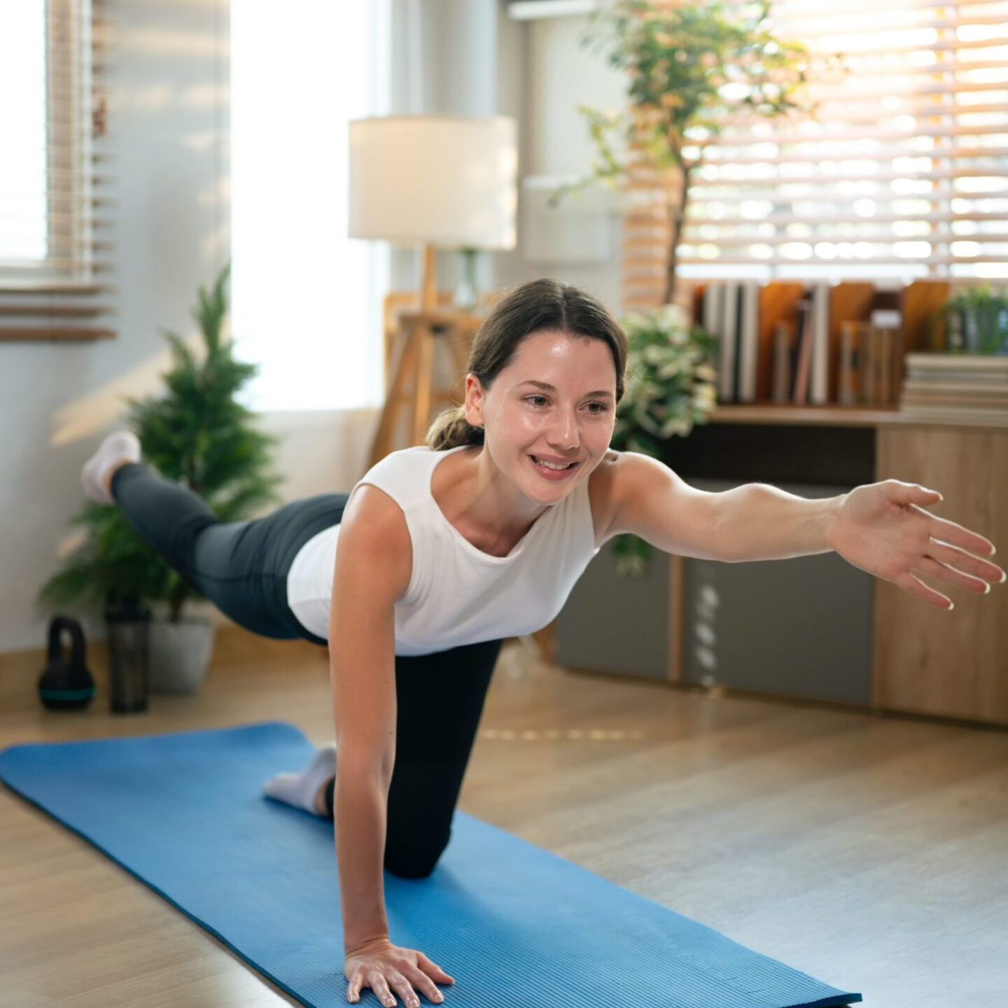 Female performing core stability balance exercise on yoga mat indoors, Practicing Bird Dog Exercise.